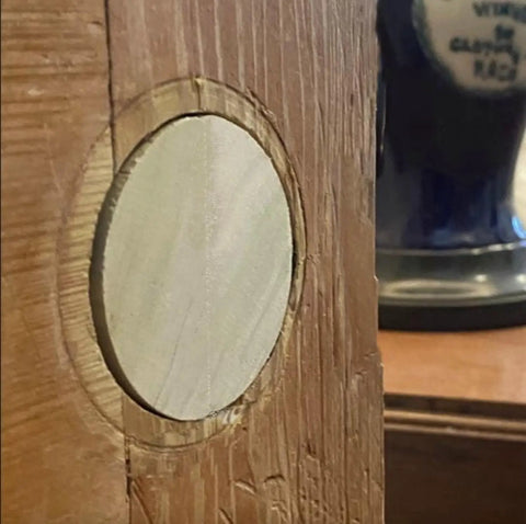 Close-up of a predrilled wooden door hole plug for two one eighth inch holes DIY ready hand made wafer style wood plug for door repair.
