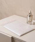 White Bubble Mailers 30 Pack 6x8 Inch Padded Envelopes for small biz shipping next to a glass bottle on a table.