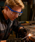Worker using welding tool while wearing Clear Anti Fog Safety Specs With Protective Goggles For Industrial Use 4 Pack.