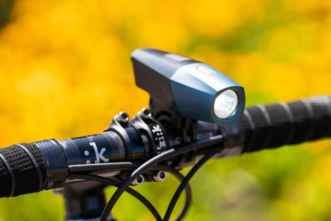 Lars Rover Power 850 USB Rechargeable Bicycle Headlight with Battery Meter mounted on bike handlebars, sunny background