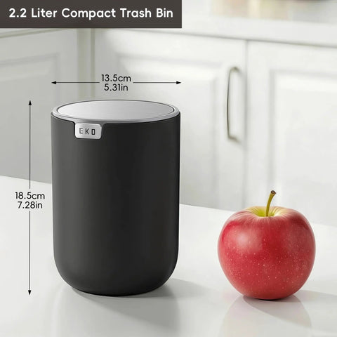 Compact Swing Top Mini Trash Can With Lid For Bathroom Vanity Countertop Desk Or Office 2.2L 7.3In Tall 5.3In Diameter Black Space Saver Tiny Trash Bin For Small Spaces next to an apple