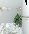 Slick Clear Acrylic Stair Handrail With Glossy Gold Brackets For Modern Homes And No Sweat Non Slip Grab Bar Kit Along Super Sturdy Wall Mounted Safety Rails For Tight Foyer Entries in a stairway with a plant.