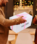 Man handing over a gift box labeled 'FASORS' with pink ribbon, suitable for storing Pink Tool Set 218-Piece Home Improvement Kit For Women