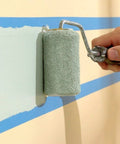 Painter using roller over blue 0.7 Inch Painter's Tape 3 Pack With 54 Yards Each For Sharp Lines And Easy Removal, creating sharp lines.