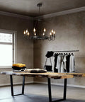 Black Industrial Wagon Wheel Chandelier Pendant Light in rustic room above a wooden table, displaying 10 lights in candle style.