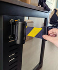 Slick Wall Mounted Retractable Warning Belt With Auto Magnetic Lock, Built Tough Five Meter Yellow And Black Barrier in use near a table.