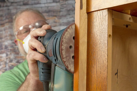 Operator using 5 Inch Heavy Duty Random Orbit Sanding Discs With Hook And Loop Backing Red Resin Aluminum Oxide 8 Hole 40 Grit 50 Pack