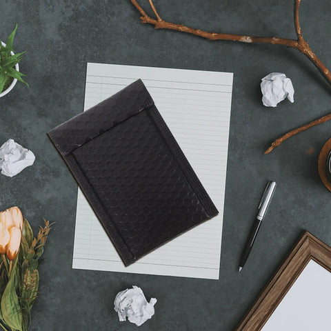 Black Padded Bubble Mailer Envelopes 12x18 on desk with stationery, ideal for small business packaging and mailing