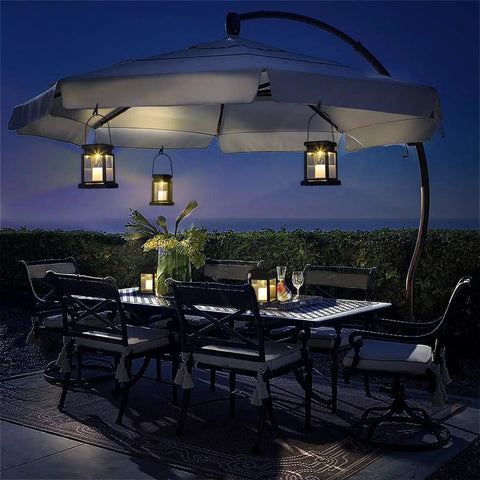 Outdoor dining area with 8 Pack Solar Hanging Lanterns Outdoor With Candle Effect Warm White Light, Easy To Hang Or Stake, under umbrella.