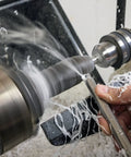 Carbide woodturning tool on a lathe shaping acrylic/resin with white shavings around.