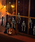 Six Pack Five Point Nine Inch Poseable Mini Skeleton Figurines Distressed Plastic Skeletons For Crafts And Halloween Decor hanging by window