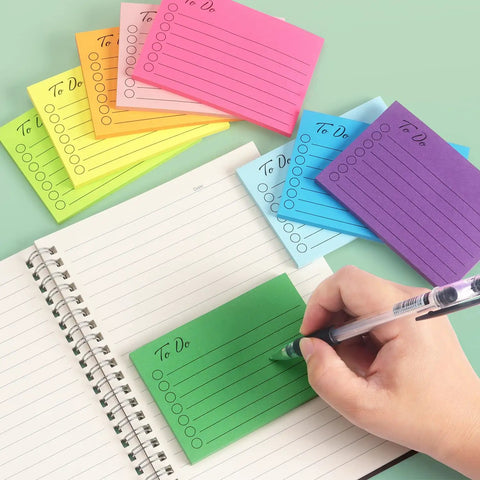 Colorful 3x4 Inch Lined Sticky Notes Pack with nine pads, fifty sheets each being used for writing on notebook in bright colors