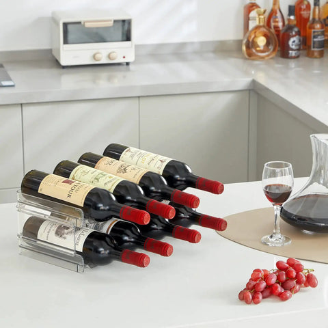 Totally Game Changer Stackable Water Bottle Organizer For Cabinet Storage, Clear Tumbler Holder That Takes 32 Oz Bottles And Energy Drinks, Saves Gobs Of Pantry Space While Keeping Your Setup Looking Fresh And Neat. Transparent bottle holder display with six stacked wine bottles on countertop.