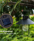2 Pack Solar Metal Hanging Lanterns With Shepherd Hooks For Outdoor LED Garden Lighting Black Pathway Porch Yard Decor That Pops Durable Weatherproof Landscape Lights hanging from a tree branch in rain with solar panel insert