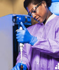 Lab technician in purple medium disposable lab jackets crafted in lightweight SMS 50 GSM 30 inch hip length with snap front knit cuffs.