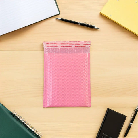 Pink Bubble Padded Mailers Self Seal Envelopes 100 Pack For Jewelry And Makeup Supplies on desk with stationery