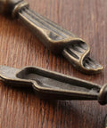 Close-up of Antique Bronze Metal Drawer Cabinet Pulls 2 Pack With Screws, Single Hole Drop Handles 0.75 X 2.36 Inches on wood surface.