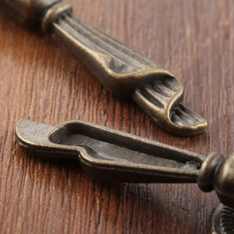 Close-up of Antique Bronze Metal Drawer Cabinet Pulls 2 Pack With Screws, Single Hole Drop Handles 0.75 X 2.36 Inches on wood surface.