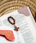 Fourteen Genuine Leather Heart Bookmarks With Uplifting Bible Verses marking pages in a book, showcasing soft texture and gold accents.