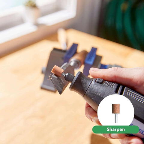Rotary tool with brown sanding drum attached, close-up in hand with a workbench vise in background.