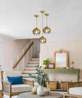 Gradient Gold Glass Pendant Light For Kitchen Island, three globe fixtures hanging in a cozy living room with warm ambience.