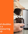 Krups Electric Coffee Grinder With 3 Oz Capacity And 200 Watt Motor Grinds Beans, Spices, And Nuts Easily, measuring cup lid in use.