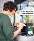Teal 250-count lens cleaning wipes box on desk beside laptop; person cleaning eyeglasses with a wipe