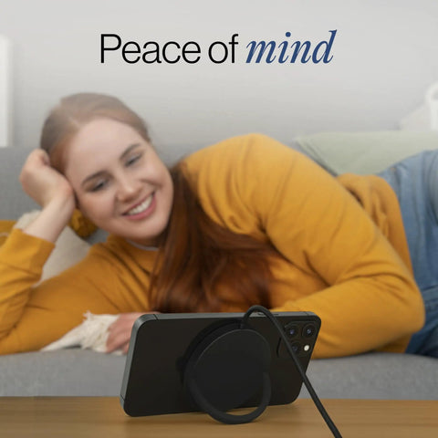 Woman smiling near phone charging with Dope Wireless Charger Pad 15W for iPhone AirPods and Android Devices, MagSafe compatible.