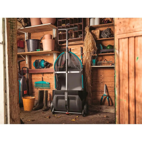 Durable Lawn Sweeper For Leaves And Grass Clippings stored in a shed, featuring 3.2 Cu Ft Mesh Hopper and upright push design.