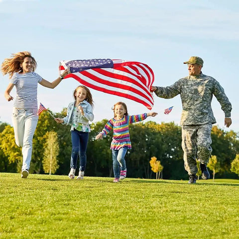 Family running with 3x5 Ft Heavy Duty Outdoor American Flag Deluxe Spun Polyester Waterproof UV Resistant Embroidered Stars in a park.