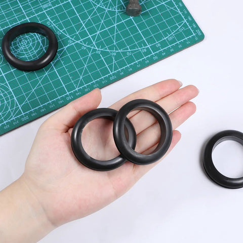 Hand holding 2 Inch Rubber Grommet Kit, 4 Pack Large Wire Hole Plugs For Electrical Boxes And Cables, on a green mat