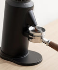 Dope Single Dose Electric Coffee Grinder Featuring 64Mm Titanium Flat Burrs And Stepless Adjustment To Nail Your Flavor Packed Espresso Routine In Sleek Black Finish with coffee grounds funneling into portafilter.