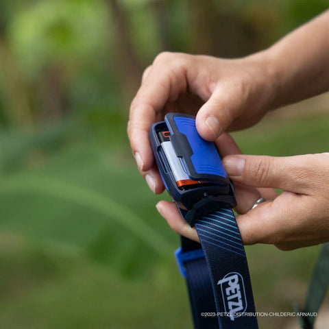 Hands inserting Core Rechargeable Battery For Hybrid Headlamps 1250 mAh Li Ion With USB Micro USB Port into headlamp