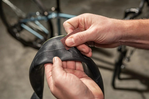 Deluxe Bike Tube Repair Kit With Tire Patches, Levers, Scuffer And Tools, cyclist repairing bike tube with scuffer