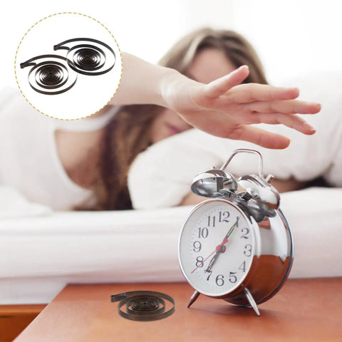 Two Piece Steel Clock Mainsprings Replacement Kit For Mechanical Clocks Wind Up Clocks beside an alarm clock on a table