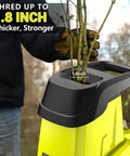 User inserting branch into Electric Wood Chipper Shredder With Fifteen Amp Motor And One Point Eight Inch Cutting Diameter