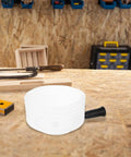 Heavy Duty Hole Saw Dust Bowl Catcher on workbench, durable material designed to clamp tightly to bits and trap dust.
