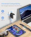Global Travel Power Adapter With 4 USB Ports And 160 Country Coverage charging a laptop, phone, camera, watch on desk.