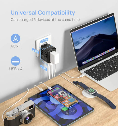 Global Travel Power Adapter With 4 USB Ports And 160 Country Coverage charging a laptop, phone, camera, watch on desk.