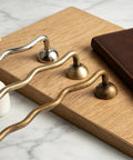 Solid Brass Cabinet Pulls With 5 Inch Hole Centers and ergonomic wave design in antique finish displayed on a wooden surface.