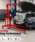 Built Tough 2 Ton Hydraulic Engine Hoist Bringing 4400 Lbs Of Serious Lifting Muscle To Your Shop With Six Swivel Wheels For Hell Of A Smooth Ride And Zero Mess Folding Crane Performance in a workshop lifting an engine.