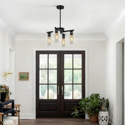 Sleek Modern Black Four Light Farmhouse Chandelier Featuring Crisp Cylindrical Glass Shades Fully Adjustable Height Industrial Pendant Fixture above entrance.