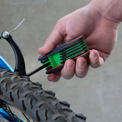 Hand using 25 Piece Folding Hex Key Set SAE And Metric With Color Coded Bodies And Labeled Sizes Allen Wrenches on bicycle