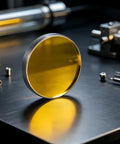 Five Layer Gold CO2 Laser Mirrors With Rock Solid Silicon Base High Reflectivity And Peelproof Electroplating For Desktop And Industrial Engravers Heavy Duty Zero Hassle Top Shelf Quality round mirror on a workbench.