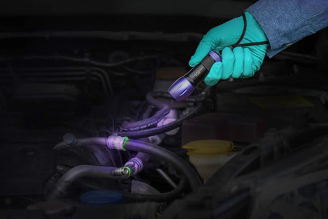 LEAKFINDER LF021 leak detection kit with dye injector and UV light, held by gloved hand near engine hoses
