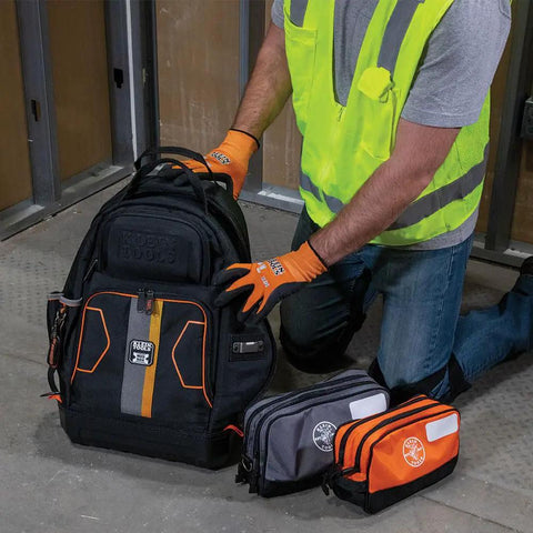Person using a black heavy-duty backpack with gray and orange dual compartment tool pouch, ideal for meters and gear.