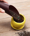 Go-To Reusable Plastic Garden Shovel Cup For Bonsai And Potted Plants 16x6 cm Cultivation Tool Spade Soil Scoop For Succulents And Fleshy Plants Handy Garden Care Essential For Plant Lovers in use filling a small yellow pot