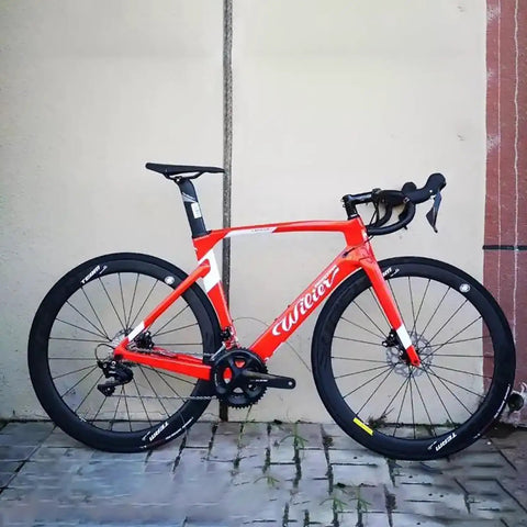 Red road bike with Classic Pro Carbon Wheelset With Deep 38, 50, 60, 88mm Depth For Rim Brake Road Bikes, parked on stone pavement.