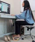 Woman using Ergonomic Wood Foot Rest With Rocker Board For Standing Desks, Supports Up To 350 Lbs, Non Slip, 18 Inch Wide under desk
