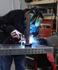 Person welding on Heavy Hitter Portable Welding Table Folding Workbench 21 X 44 Inches Flat Steel Surface Clamping Grid.